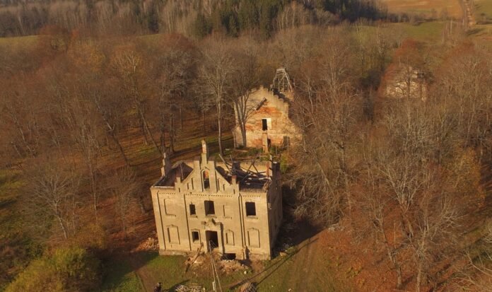 Apleistas dvaras rudenį su matomomis medžių šakomis ir griuvėsiais.