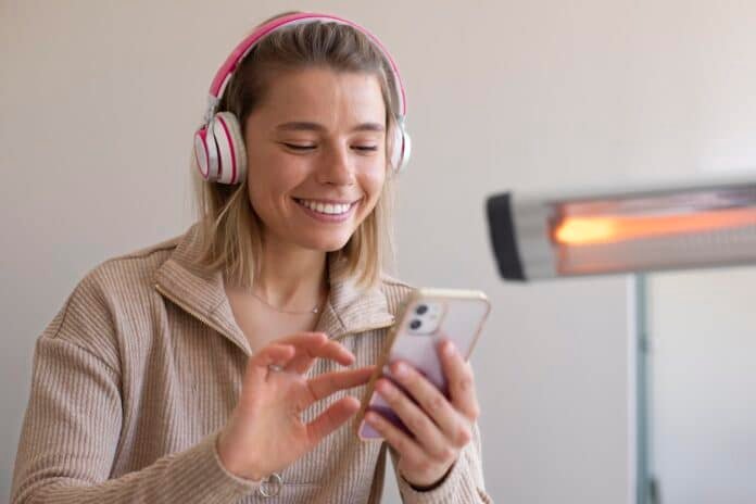 Internetinis radijas ryte moteris su ausinėmis klausosi per telefoną