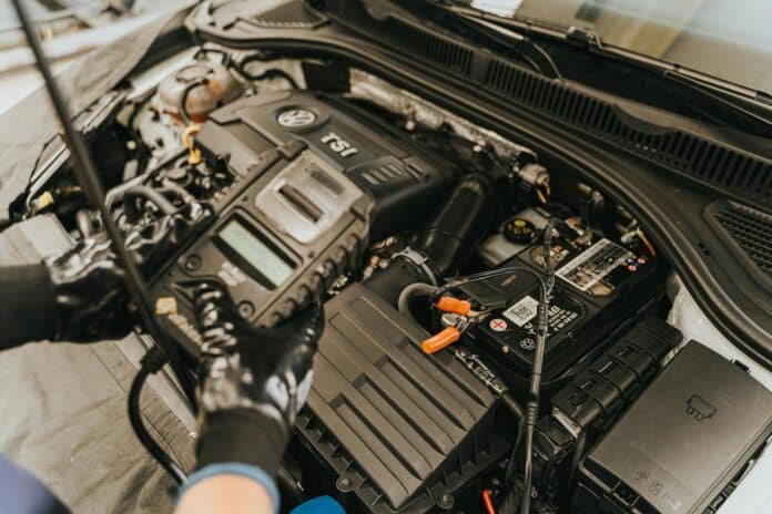 Mechanikas tikrina AGM akumuliatorių po automobilio kapotu – patikimas, ilgaamžis ir Start-Stop sistemoms tinkantis sprendimas.