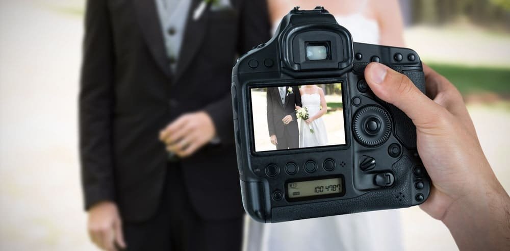 Fotografas įamžina jaunavedžių vestuvių akimirką per fotoaparato ekraną – prisiminimai, kurie išliks visam gyvenimui.