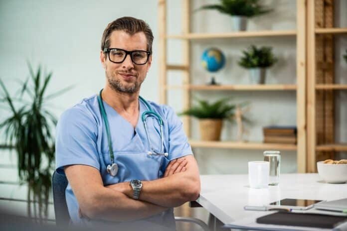 Gastroenterologas su uniforma ir stetoskopu, pasiruošęs konsultacijai savo kabinete.